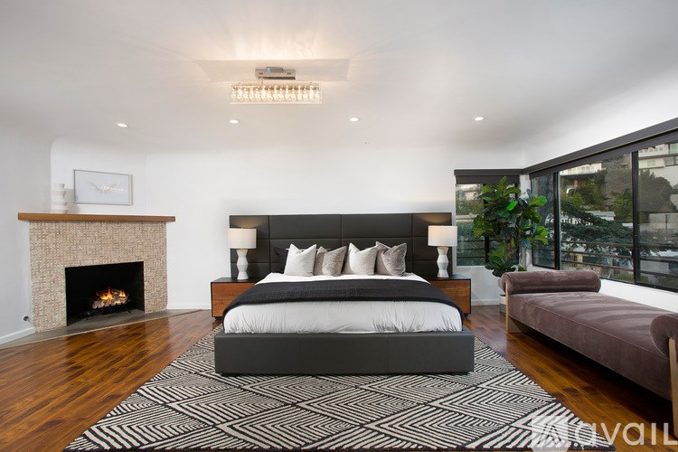 A modern bedroom with a large bed and a fireplace.