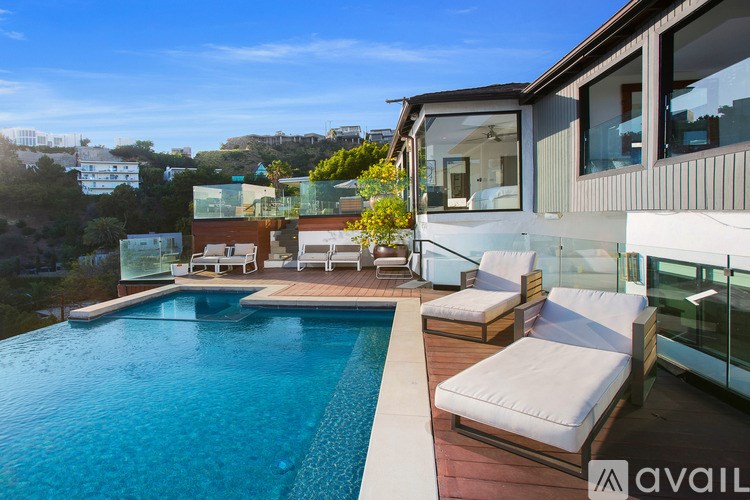 A modern house with a pool and lounge chairs.