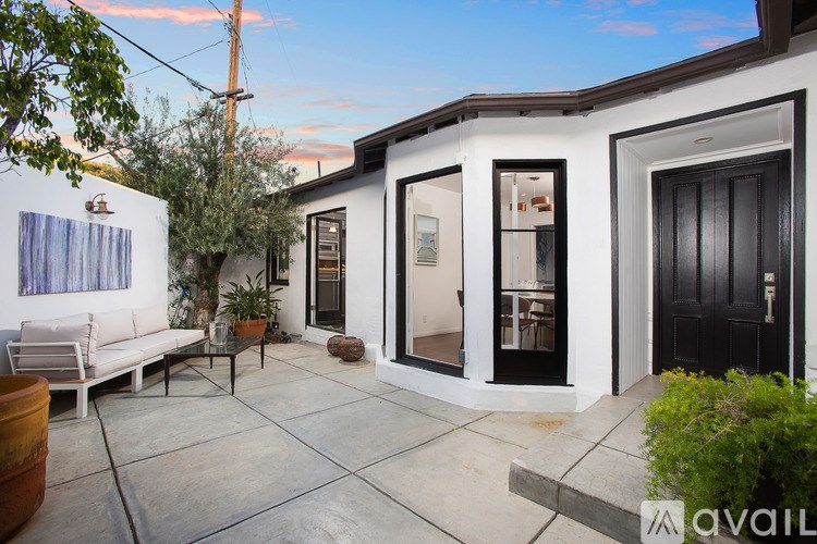 A patio area with a white couch and a table with a plant on it.