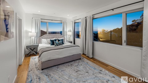 A bedroom with a large bed and a view of the mountains outside the window.