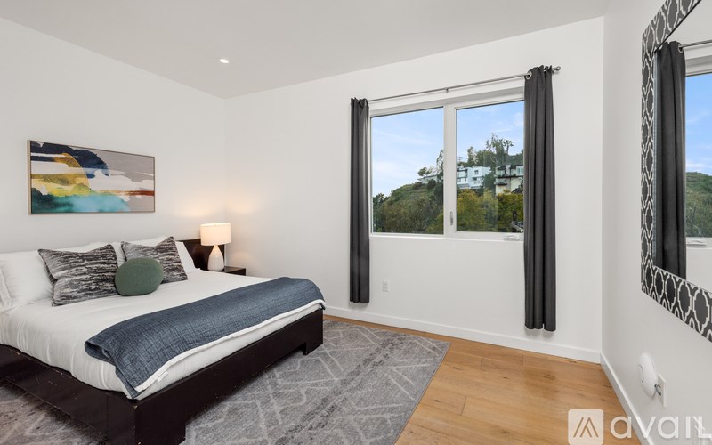 A bedroom with a large bed and a painting on the wall.