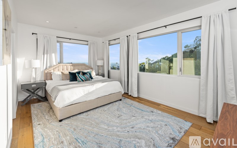 A bedroom with a large bed and a view of the outdoors through the window.