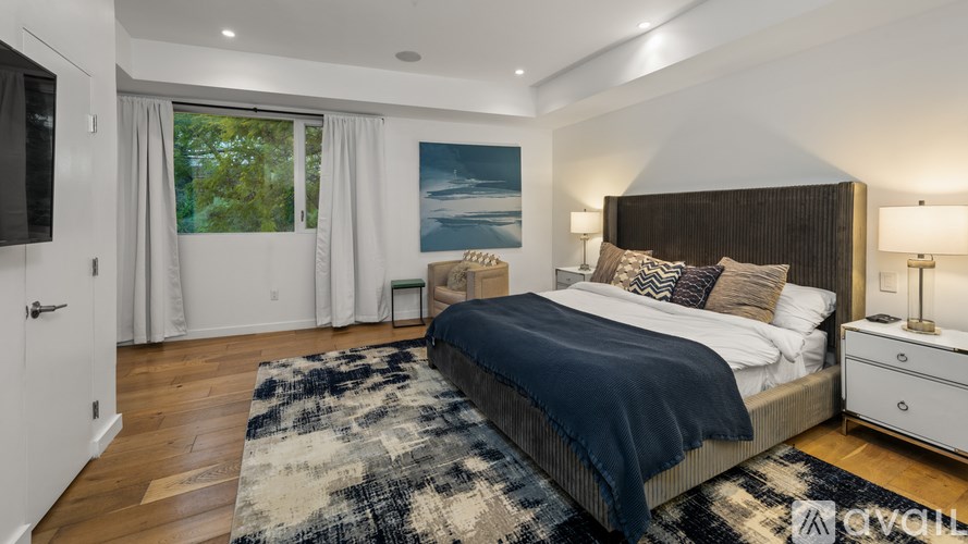 A bedroom with a large bed and a painting on the wall.