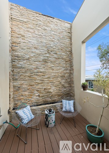A balcony with a stone wall and two chairs.