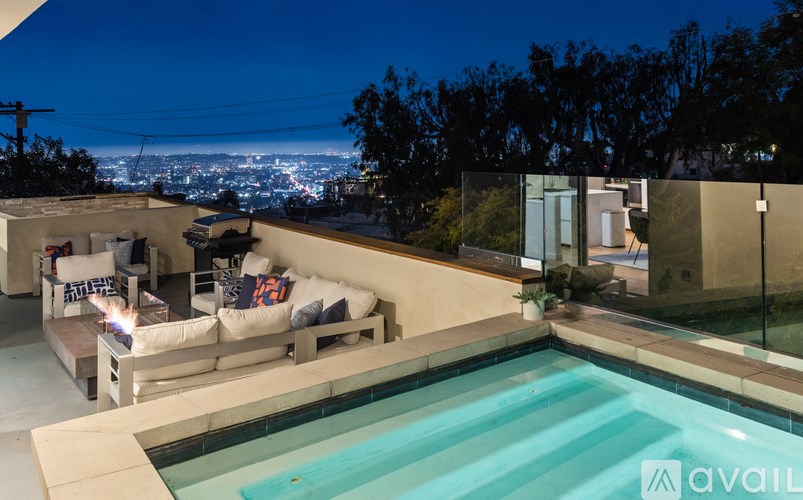 A modern outdoor living space with a pool and a view of the city at night.