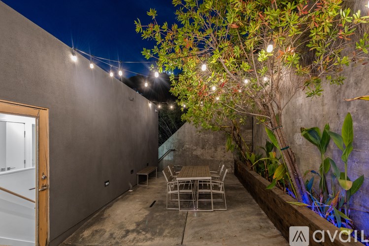 A patio with a table and chairs is illuminated by string lights.