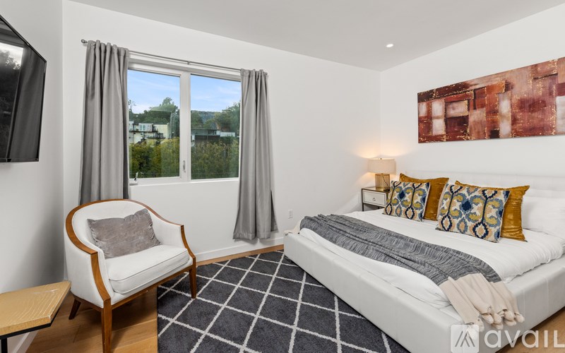 A bedroom with a bed, chair, and window.