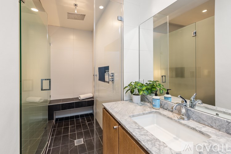 A modern bathroom with a glass shower stall and a marble countertop.