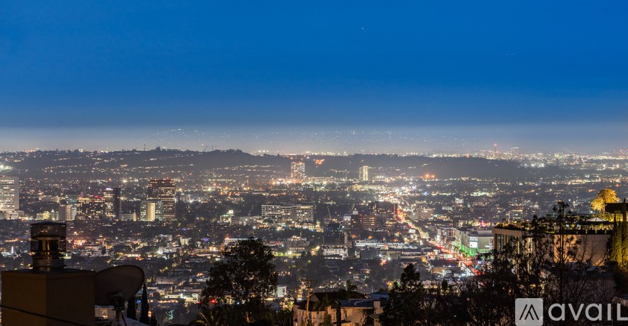 A cityscape at night with buildings illuminated and a satellite dish visible.