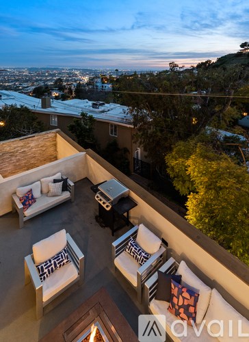 A patio with a table and chairs overlooking a cityscape at dusk.