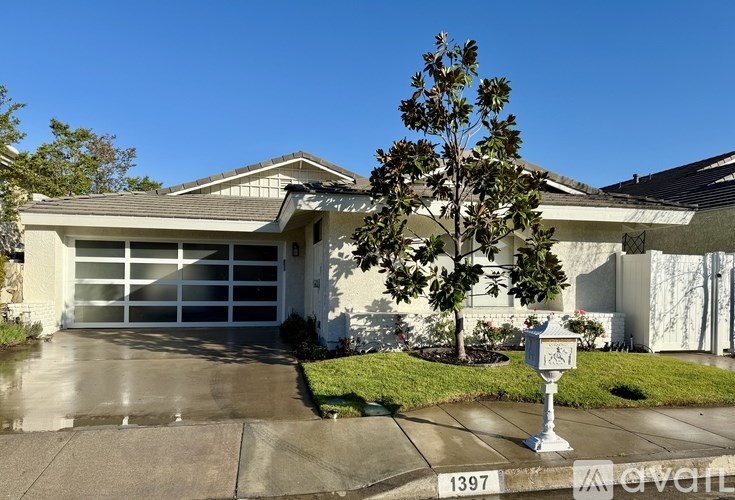 A house with a white garage door and a tree in front of it.