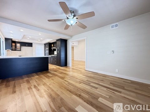 A spacious room with a ceiling fan and wooden flooring.