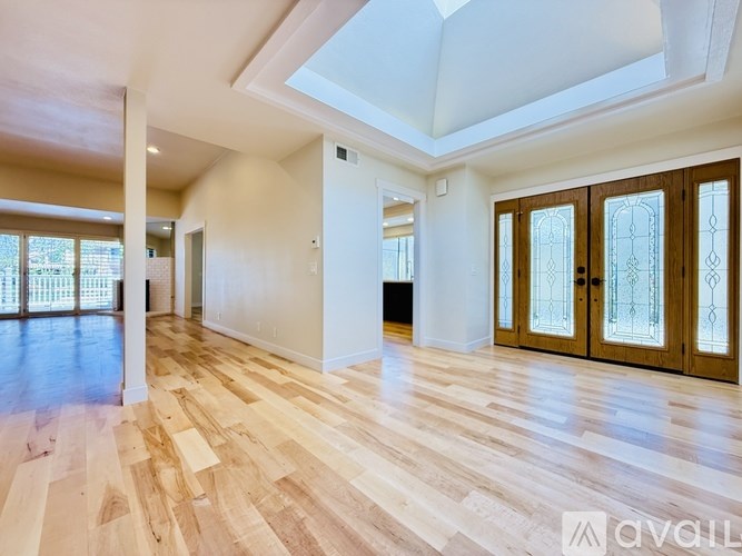 A spacious room with wooden floors and a skylight.