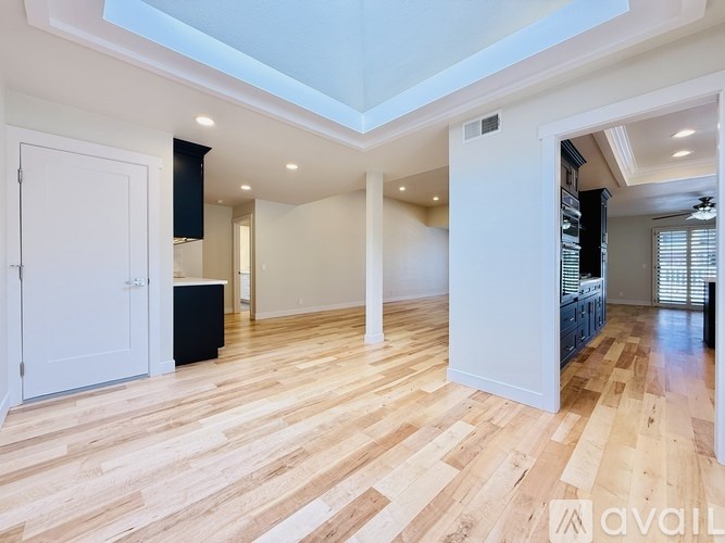 A spacious room with wooden flooring and white walls.