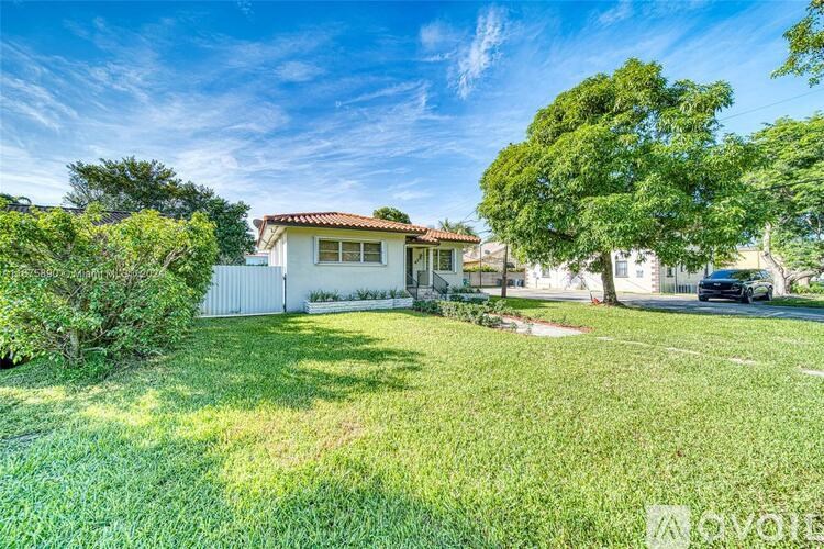 A house with a white fence and a tree in front of it.