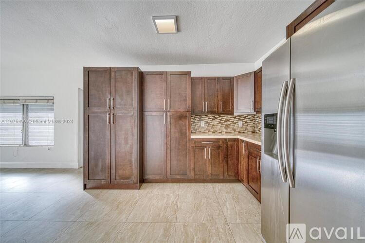 A kitchen with wooden cabinets and a stainless steel refrigerator.