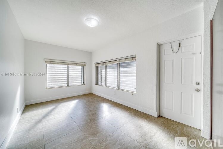 A white room with a door and two windows.