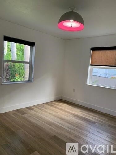 A room with wooden flooring and a window with blinds.