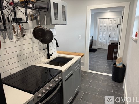 A kitchen with a black stove top and a white tiled backsplash.