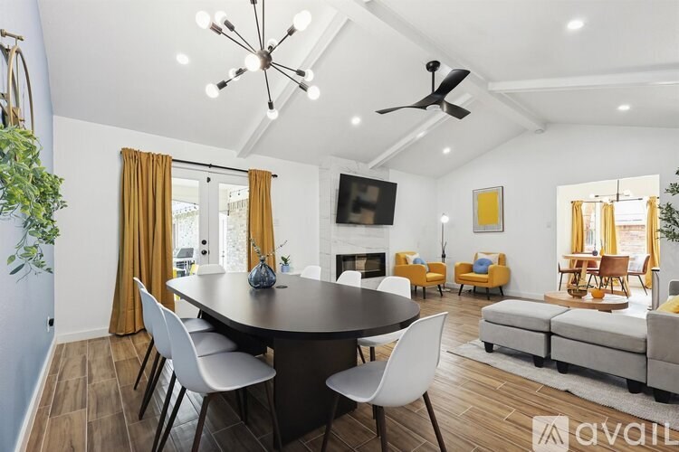 A modern dining room with a black table and white chairs.