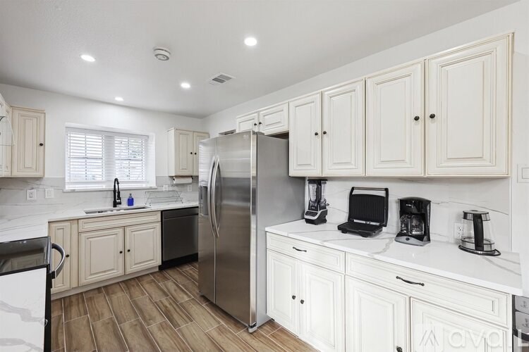 A kitchen with white cabinets and a stainless steel refrigerator.