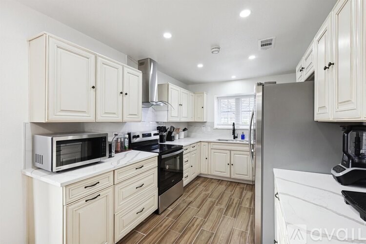 A kitchen with white cabinets and a wooden floor.