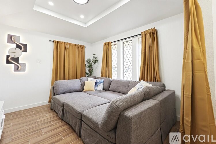 A living room with a grey sofa and yellow curtains.