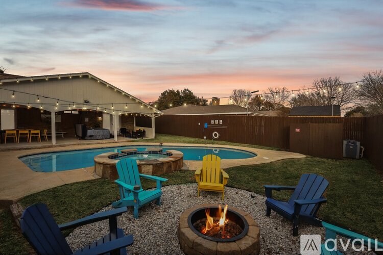 A backyard with a fire pit and chairs around a pool.