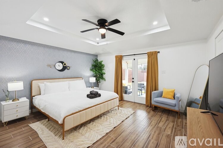 A bedroom with a large bed, a ceiling fan, and a television.