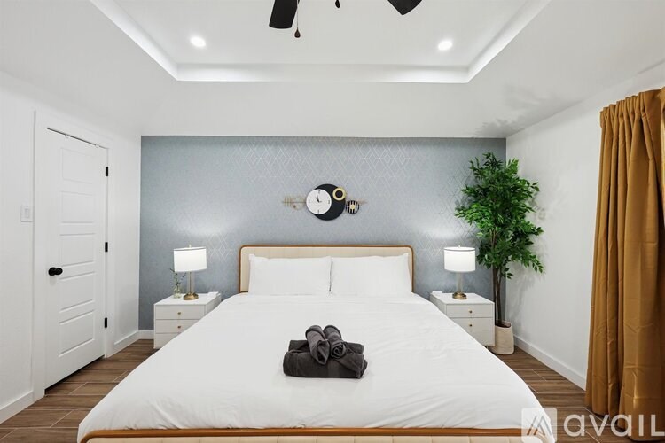 A bedroom with a large bed, a ceiling fan, and a plant.
