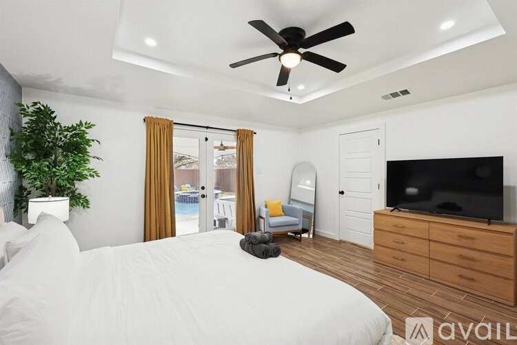A bedroom with a large bed, a ceiling fan, and a television.