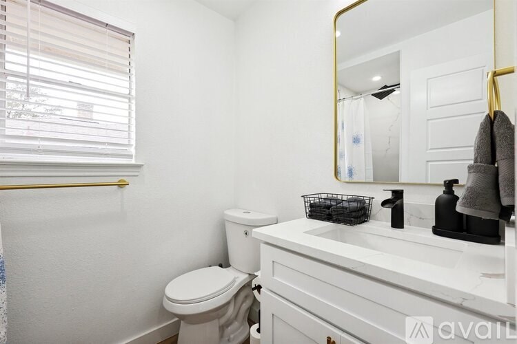 A bathroom with a toilet, sink, and mirror.