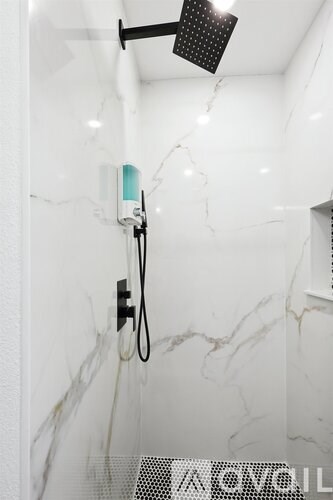 A shower head with a hand held shower attached to the wall.