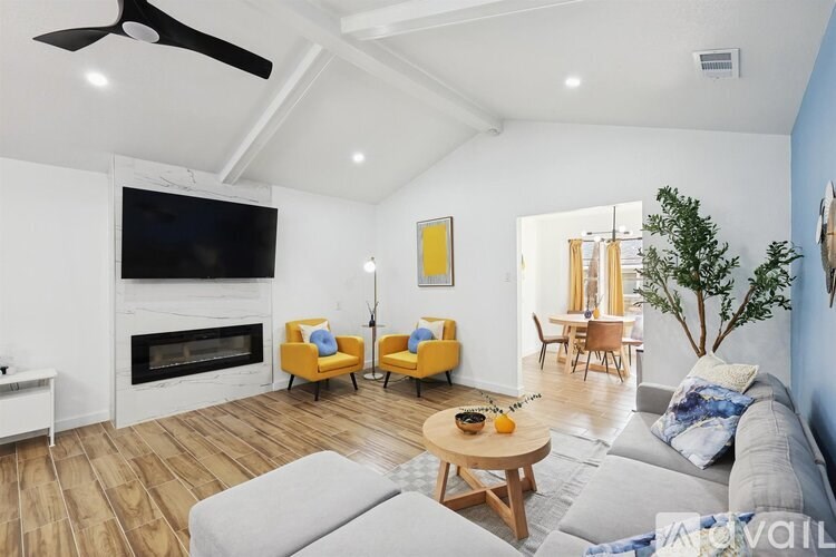 A living room with a grey couch, yellow chairs, and a white fireplace.