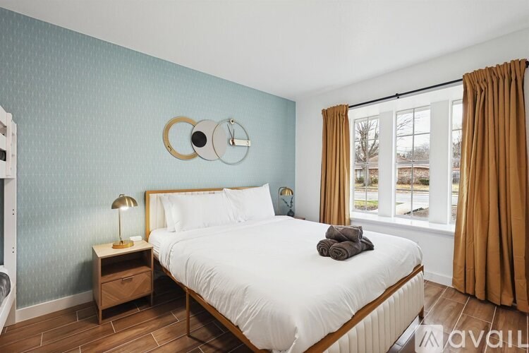 A bedroom with a large bed, a nightstand with a lamp, and a mirror on the wall.