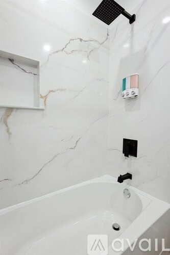 A white bathroom with a marble wall and a white tub.