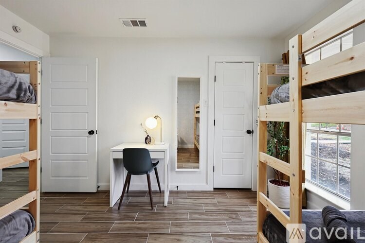 A room with bunk beds and a desk with a chair.