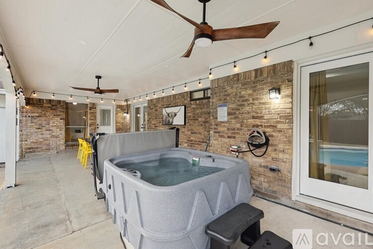 A hot tub is in the middle of a room with a ceiling fan and lights.