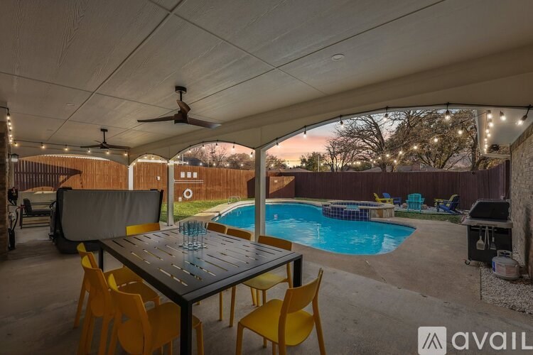 A patio with a table and chairs and a pool.