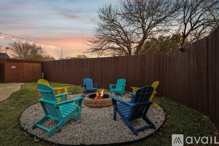 A backyard with a fire pit and chairs.