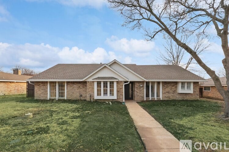 A house with a lawn and a tree in front of it.