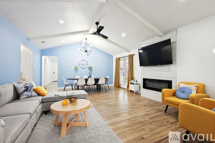A living room with a grey couch, yellow chairs, and a white fireplace.