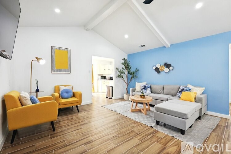 A living room with a yellow chair and a grey couch.