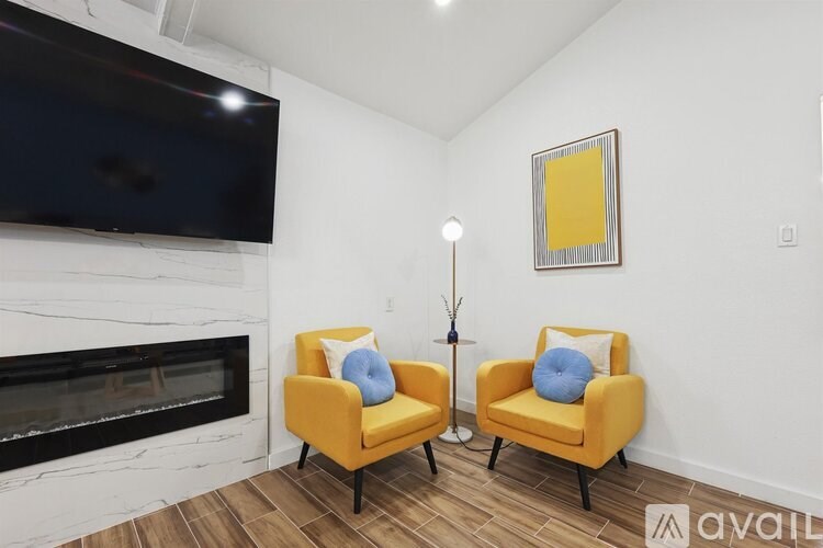 Two yellow chairs with blue pillows are in front of a fireplace.