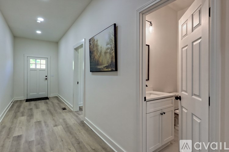 A hallway with a wooden floor and white walls.