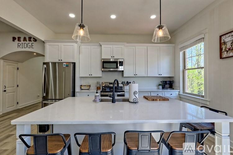 A kitchen with white cabinets and a white island with four chairs.