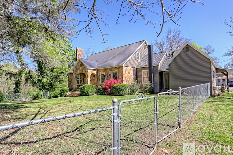 A house with a grey roof and a fence in front of it.