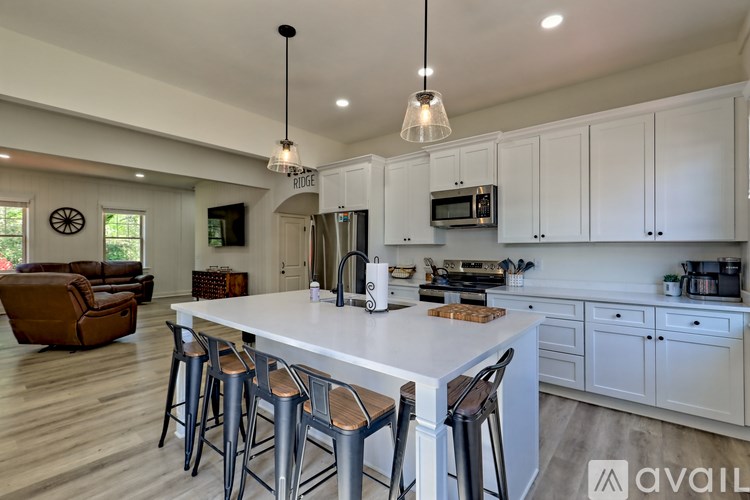 A kitchen with white cabinets and a large island with bar stools.