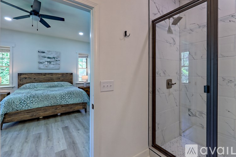 A bedroom with a bed and a shower with a glass door.