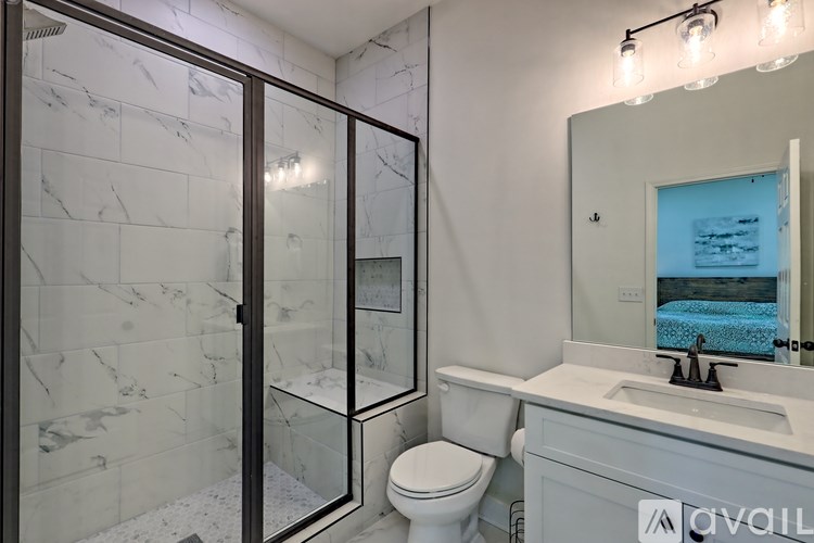 A bathroom with a marble tile shower and a white toilet.